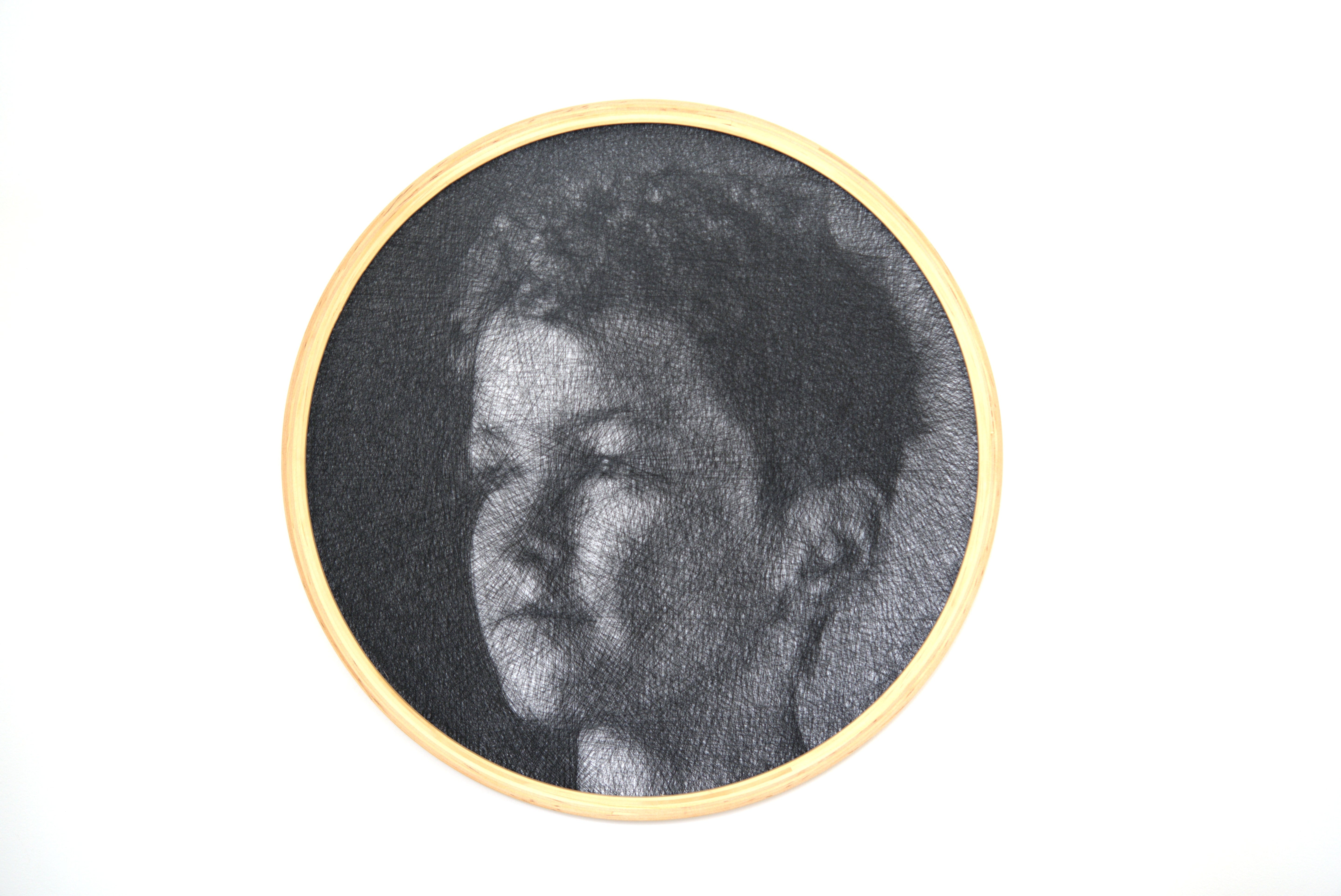 Circular black and white portrait of a person with a wooden frame on a white background